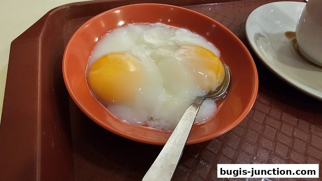 A close-up shot of two soft-boiled eggs in an orange bowl with a spoon.