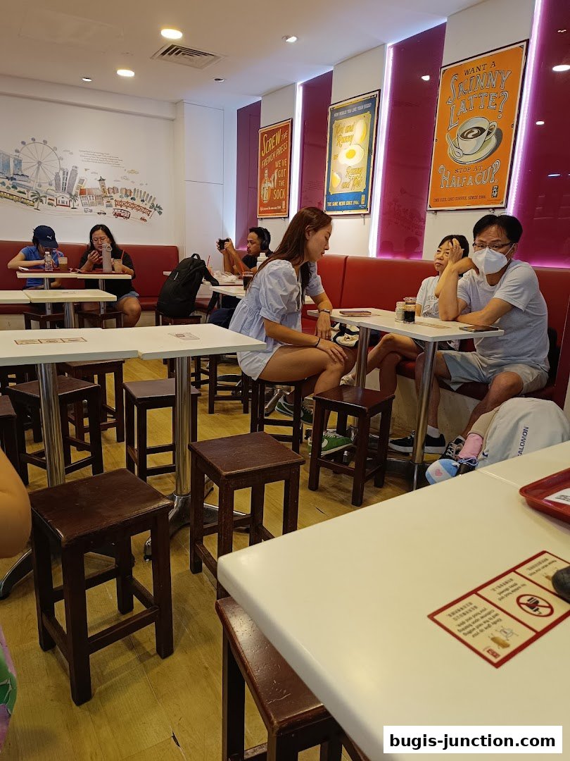 People dining at Ya Kun Kaya Toast, with vintage-style posters on the wall.