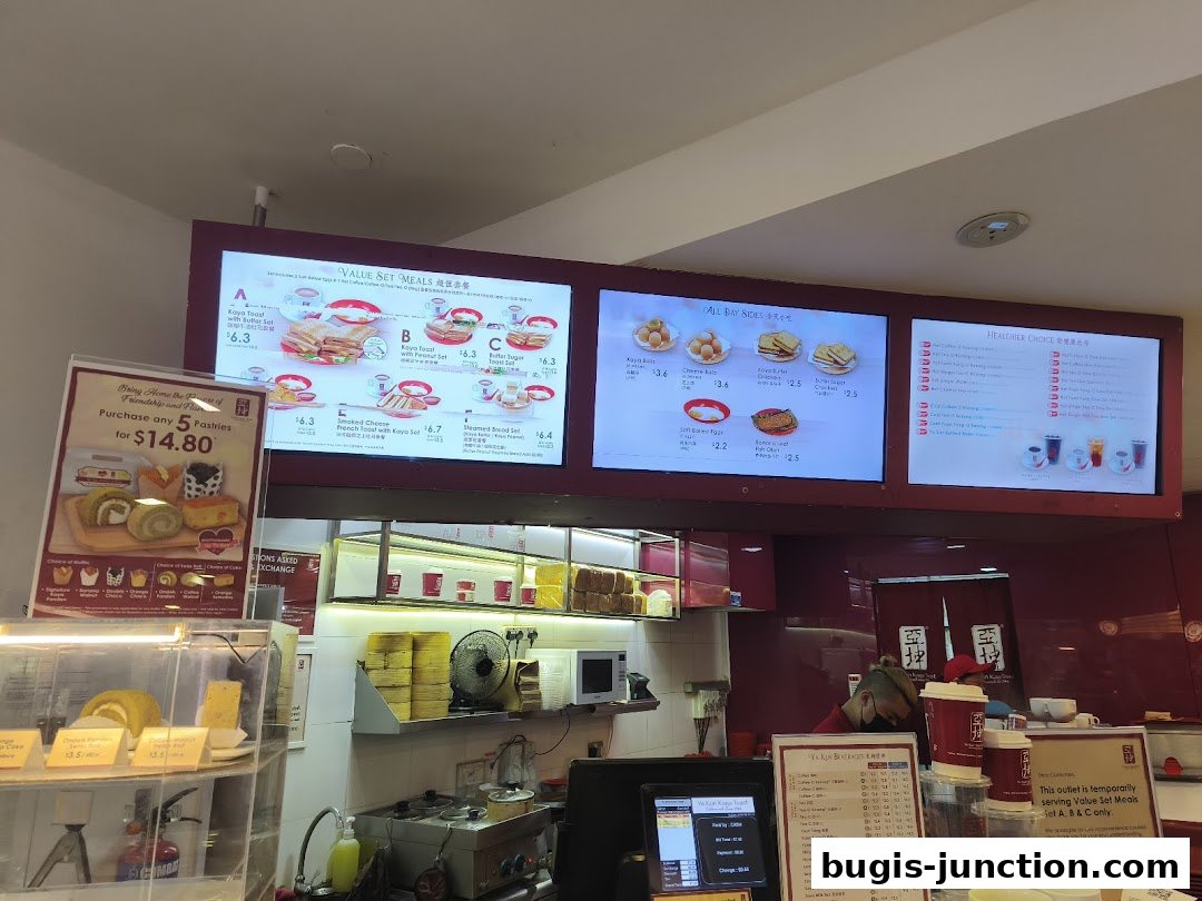 A Ya Kun Kaya Toast shop interior with digital menus displaying food and drink options.