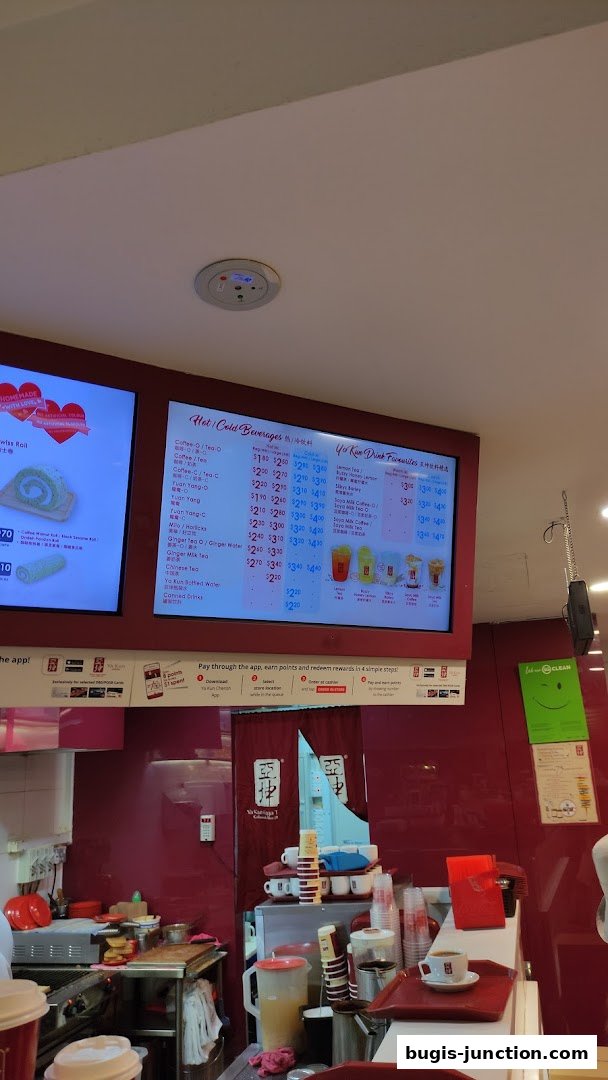 A digital menu board displaying hot and cold beverages and drink favorites at Ya Kun Kaya Toast.