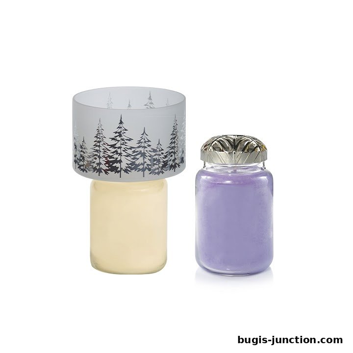 Two Yankee Candle jars, one with a frosted tree-patterned shade and a cream candle, the other with a purple candle and decorative lid.