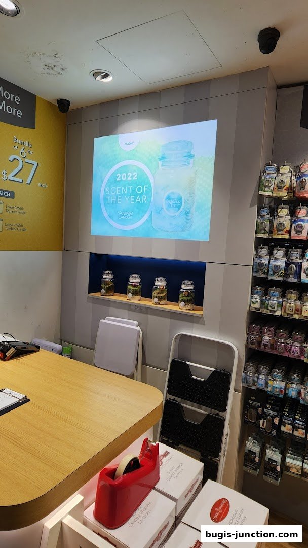 Interior of a Yankee Candle store showcasing a "Scent of the Year" display and various candle products.