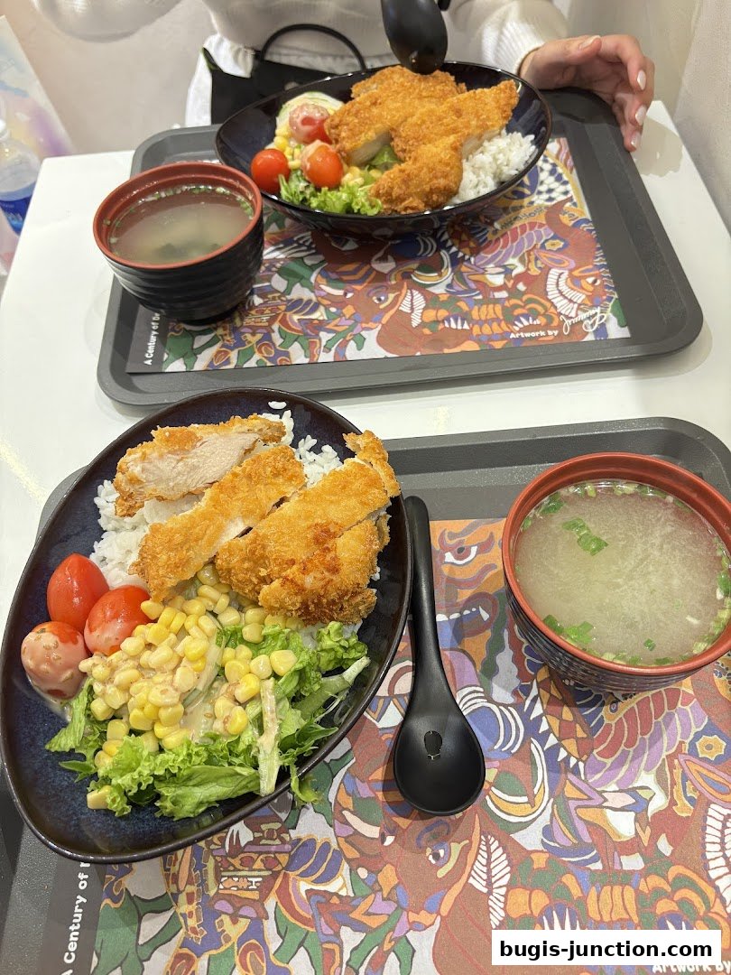Two bowls of Japanese curry rice with fried chicken, salad, and miso soup.