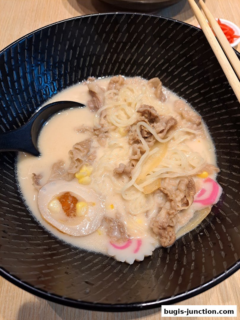 A steaming bowl of Yoshinoya's signature beef ramen with a soft-boiled egg and narutomaki.