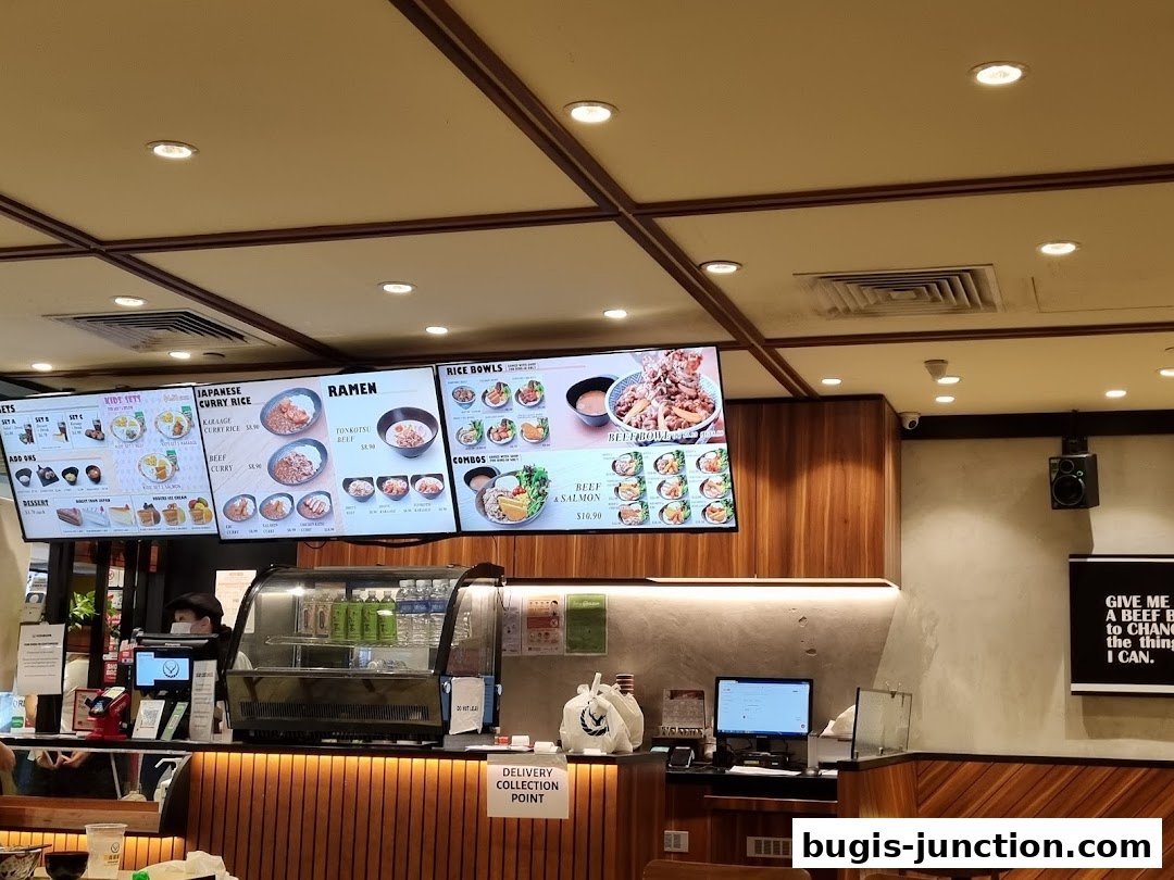 Digital menu boards displaying Japanese food items like curry rice, ramen, and beef bowls.