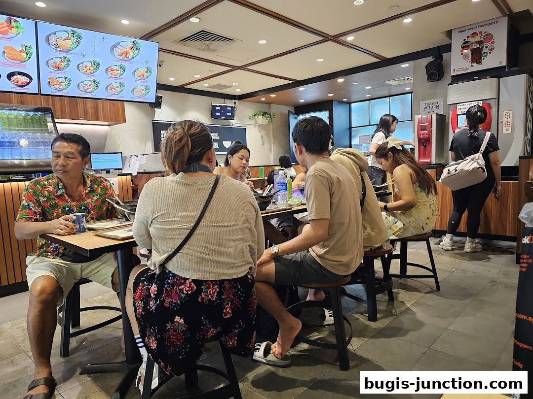 Diners enjoy meals at Yoshinoya Bugis Junction, with a digital menu displaying food options.